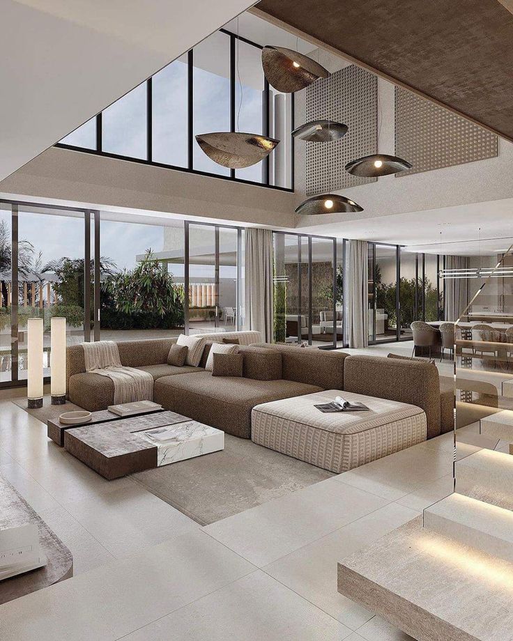 Modern living room with large sectional sofa, stylish lighting, floor-to-ceiling windows, and indoor plants.