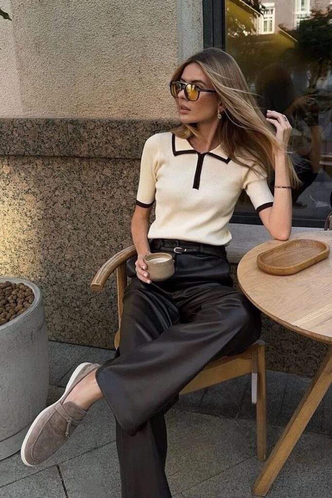 Stylish woman in sunglasses enjoying coffee at an outdoor cafe table, wearing chic outfit with leather pants.
