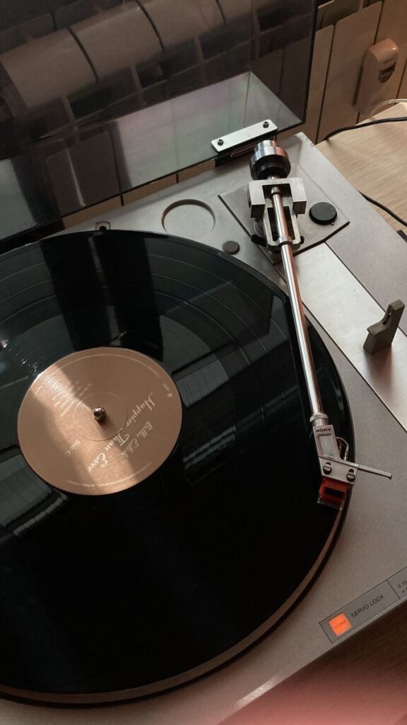 Vintage turntable playing a vinyl record in a cozy room setting.