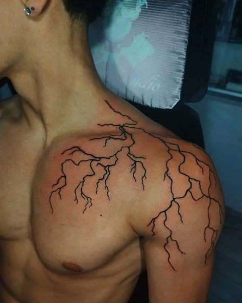 Abstract lightning tattoo on a man's bare shoulder and chest, showcasing intricate branch-like designs in black ink.