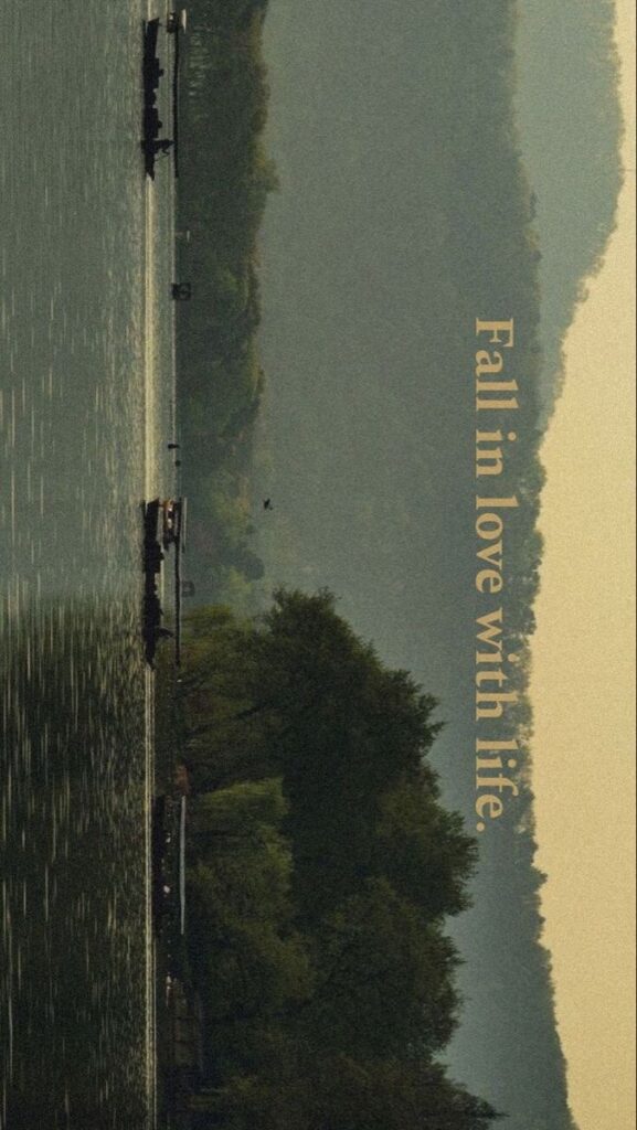 Serene lake with boats and lush green hills; Fall in love with life message.