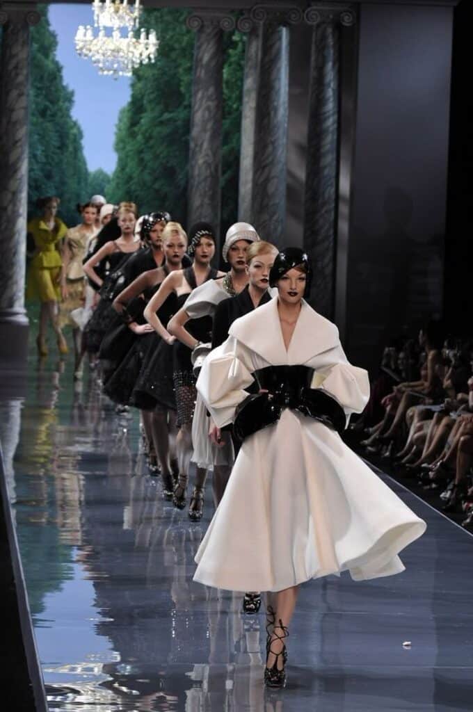 Models walking in chic monochrome outfits on a fashion runway, elegant and glamorous setting.