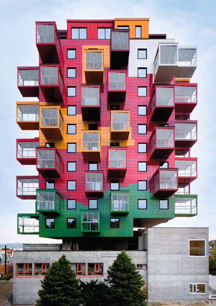 Colorful modern apartment building with protruding balconies and vibrant red, yellow, and green facade.