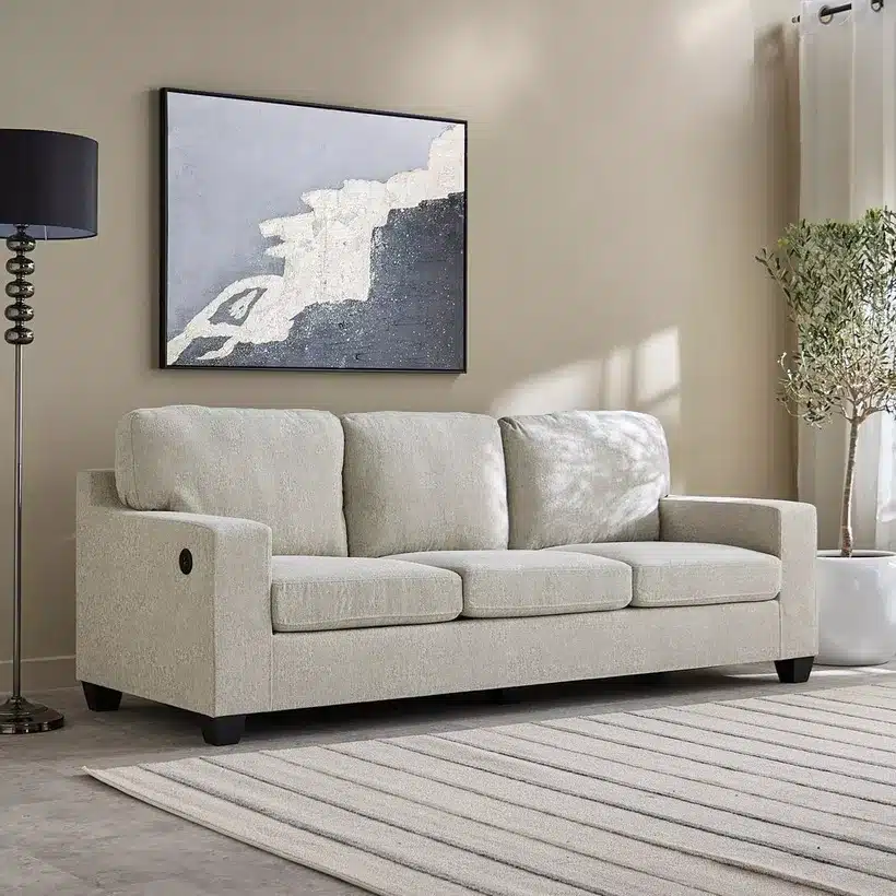 Beige sofa in modern living room with abstract painting and plants, enhancing cozy and stylish home decor ambiance.