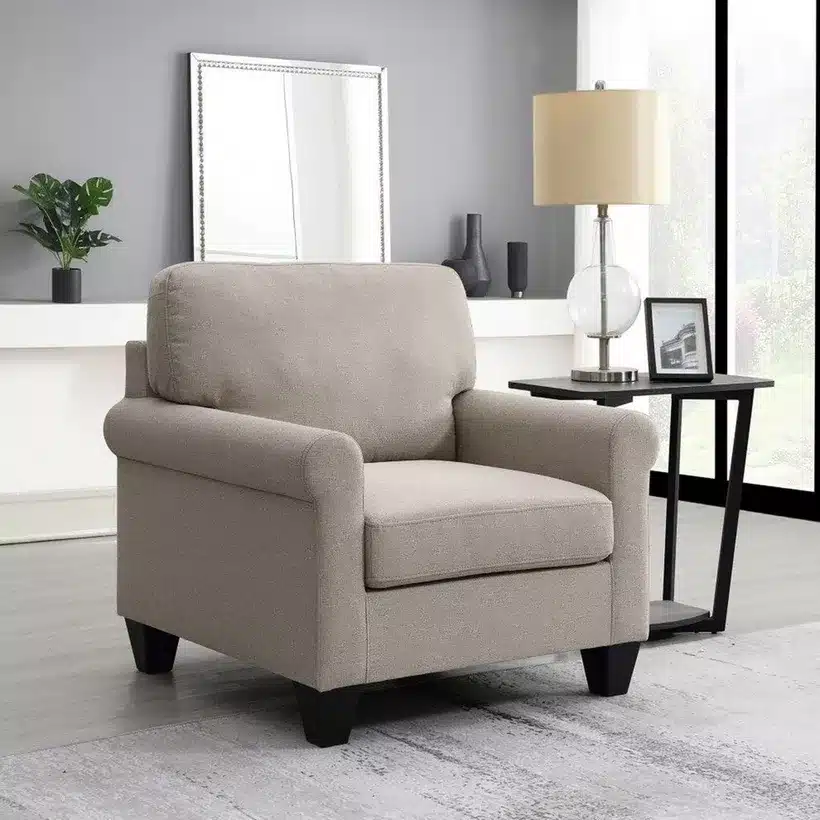 Modern gray armchair next to a side table with a lamp in a stylish living room setting.