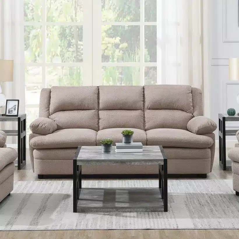 Cozy beige sofa set in a bright living room with a modern coffee table, potted plants, and large window views.