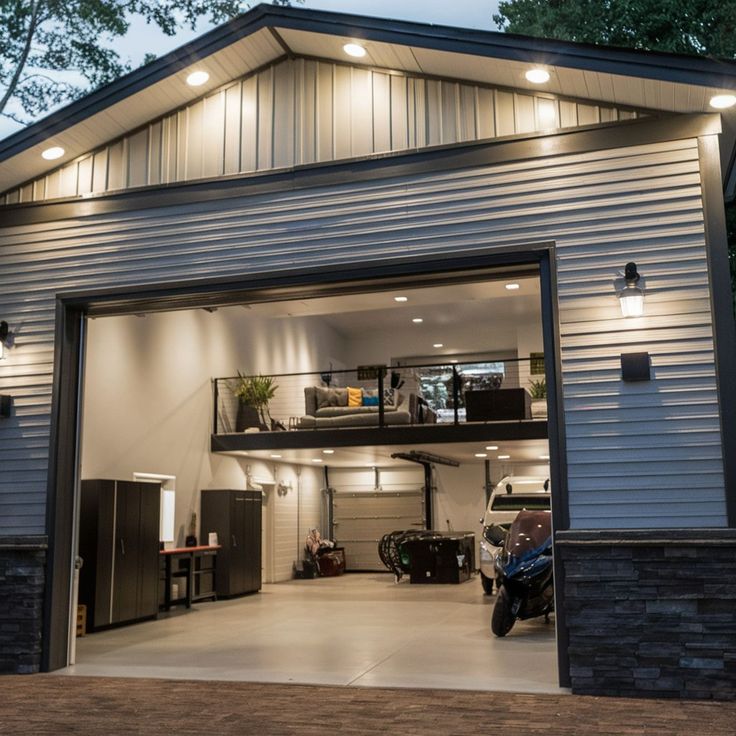 Modern garage with loft, featuring open doors, a motorcycle, and a spacious interior at dusk.