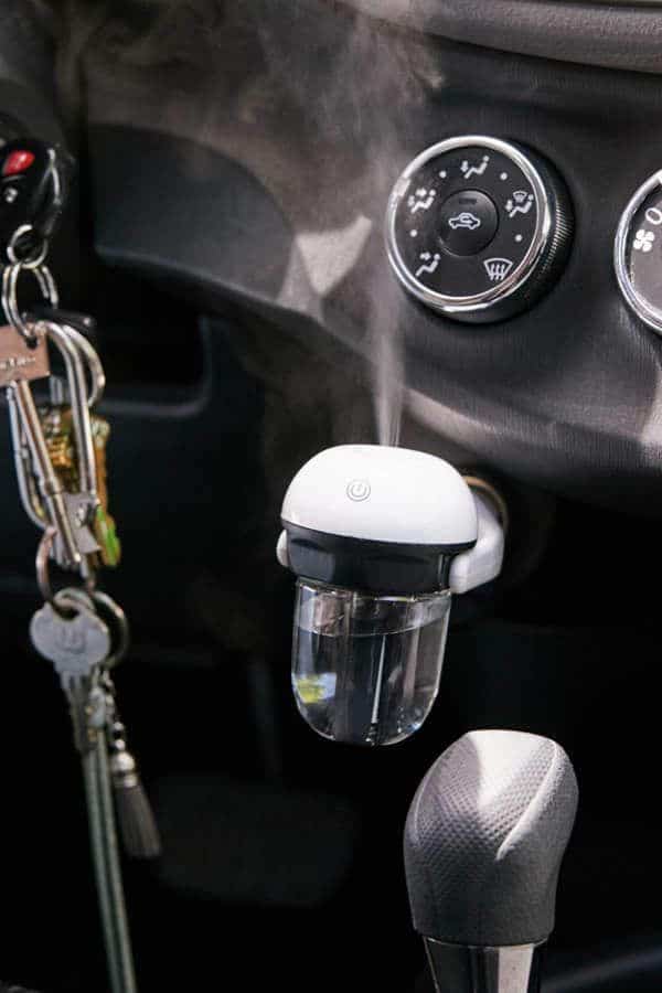 Car air purifier with keys, dashboard controls, and gear shift visible, promoting a fresh, clean environment.