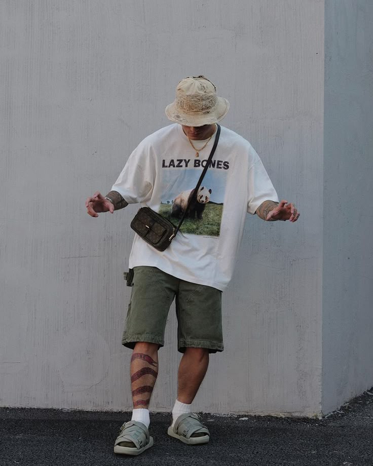 Casual streetwear outfit featuring a panda tee, olive shorts, bucket hat, crossbody bag, and sandals.