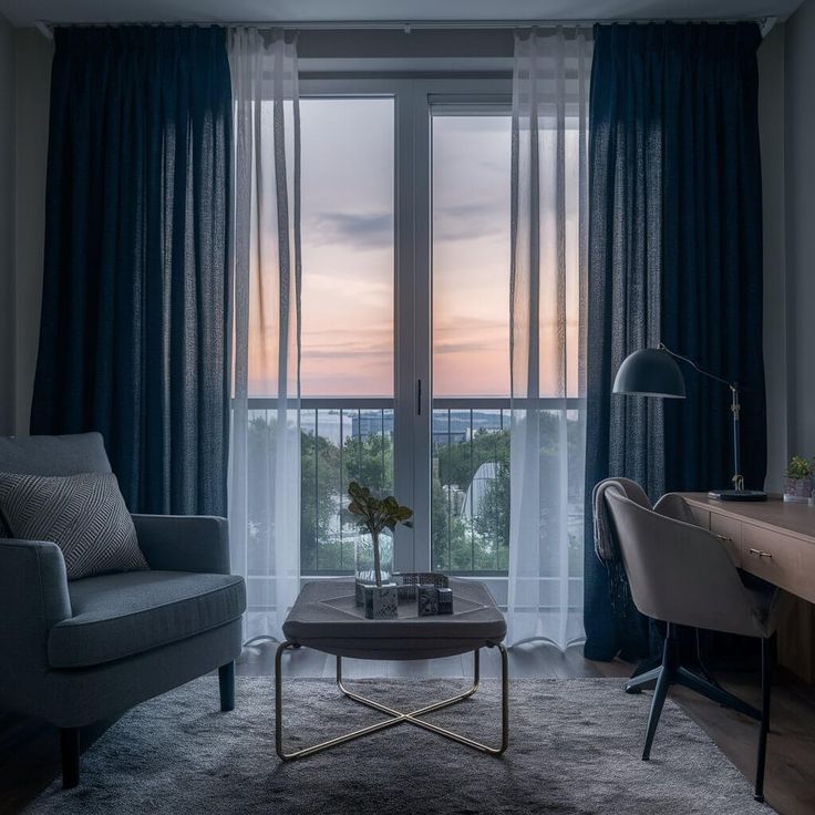 Cozy living room with modern furniture overlooking scenic sunset through large windows.