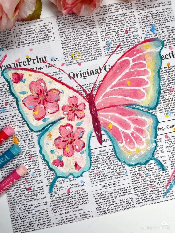 Colorful butterfly painting over newspaper with vibrant flowers on wings. Art supplies visible.