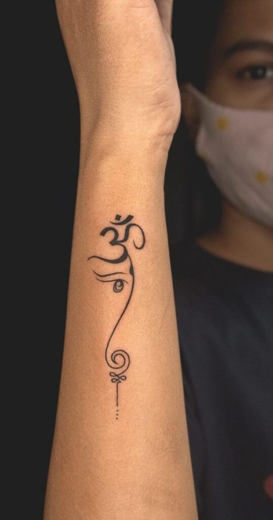Arm tattoo featuring an elegant Om design with intricate linework and dots, symbolizing spiritual connection.