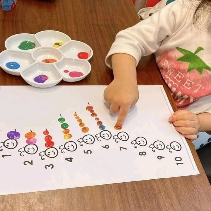Child painting colorful caterpillars by numbers, teaching counting and colors with paintbrush.