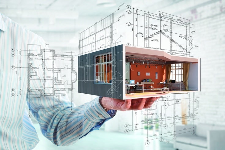 Hand holding architectural model with floor plans, showcasing modern interior design and construction blueprint.