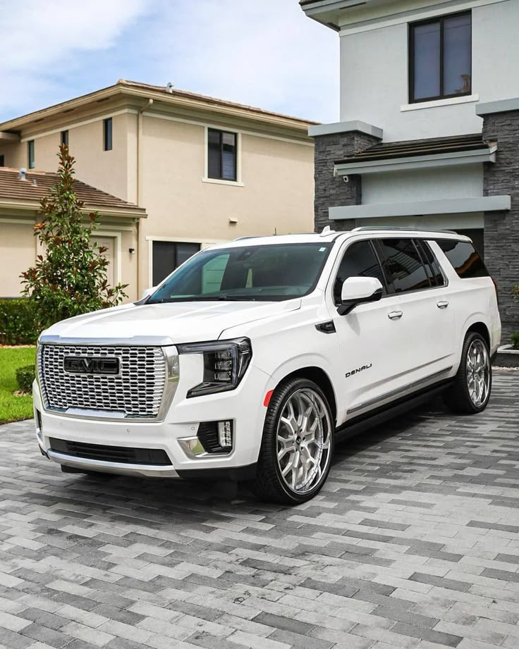 White luxury SUV parked in front of modern home on a sunny day.