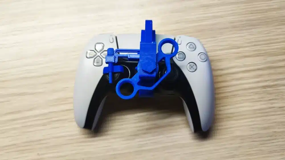 Blue 3D-printed attachment on a gaming controller on a wooden surface.