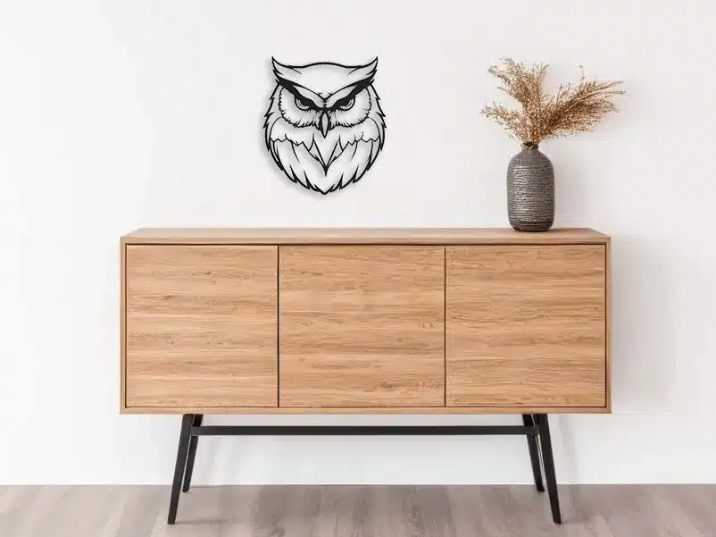 Modern wooden sideboard with owl wall decor and vase on a white backdrop. Minimalist interior design.