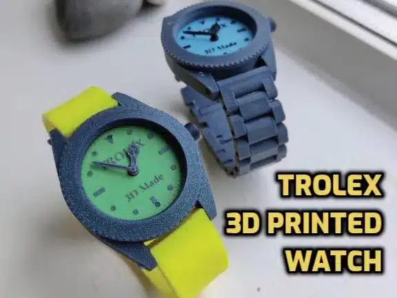 3D printed watches by Trolex with blue and yellow straps on a windowsill.