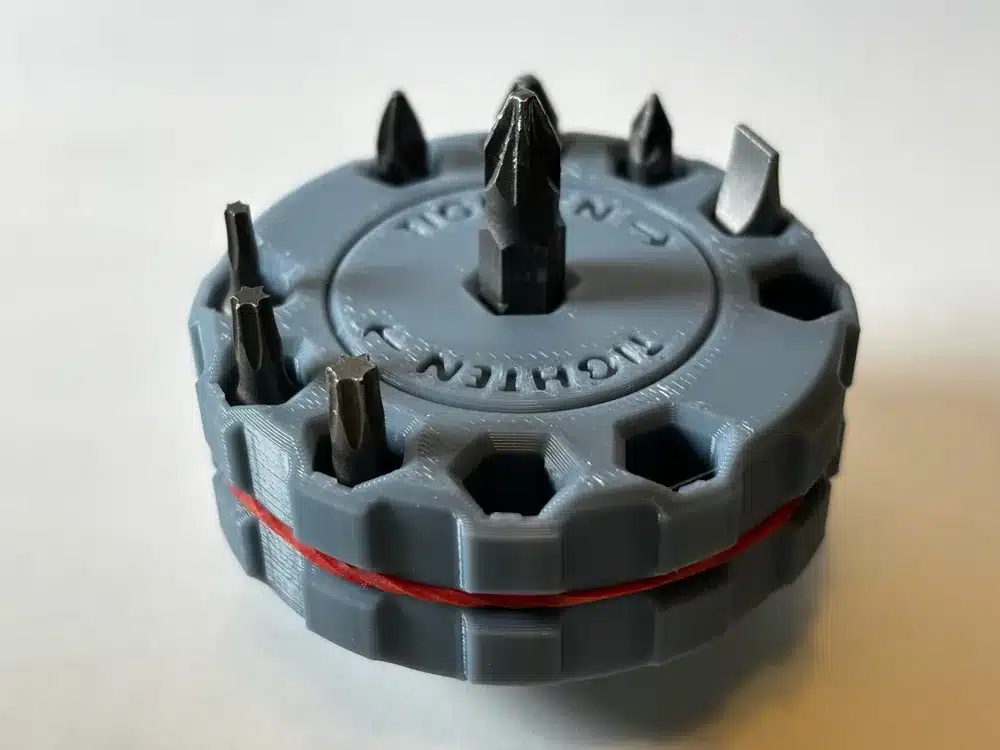 Round 3D-printed screwdriver bit holder with multiple bits set against a white background.