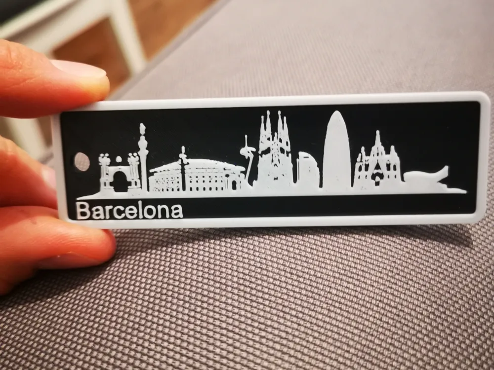 Barcelona skyline keychain with iconic landmarks, held in hand.