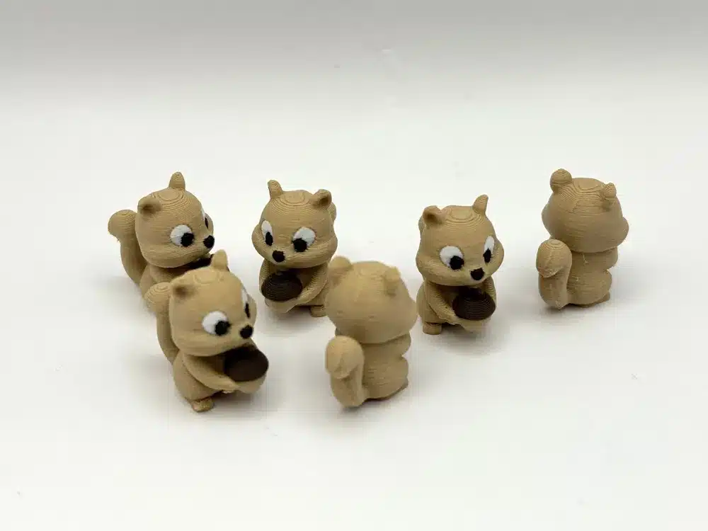 Six cute squirrel figurines holding acorns, arranged in a playful circle on a white background.