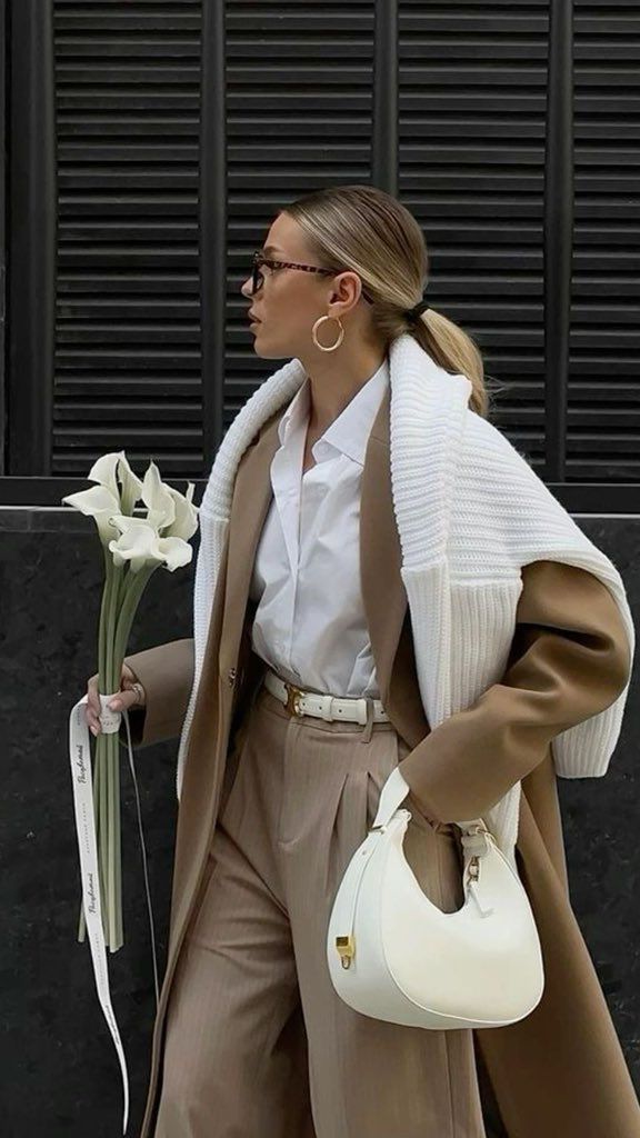 _ - 2025-06-03T122741545 Stylish woman in beige coat holding white flowers and bag, showcasing fashion and elegance. | Sky Rye Design Stylish woman in beige coat holding white flowers and bag, showcasing fashion and elegance.