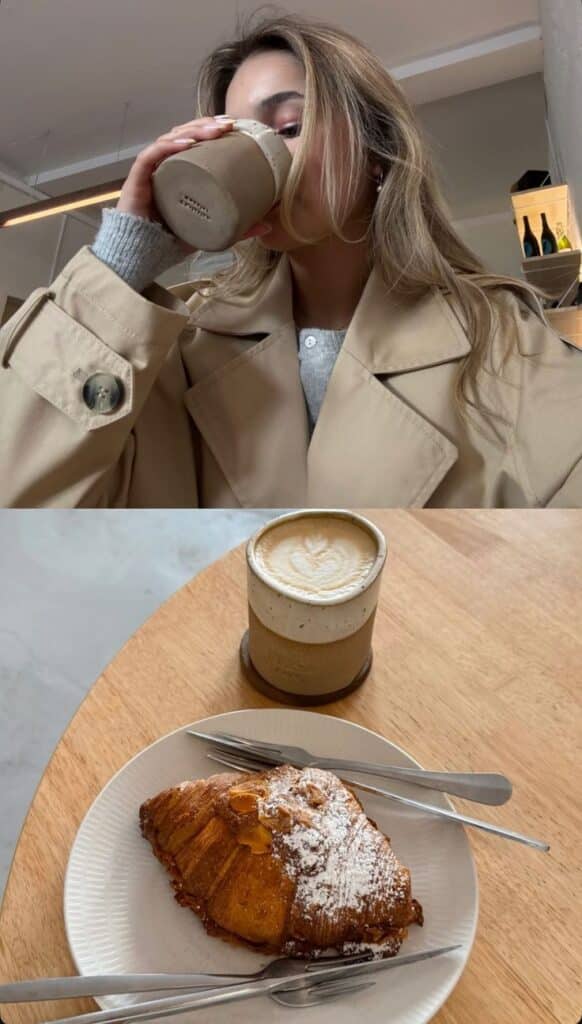 Woman in a cafe enjoying coffee and a croissant on a wooden table. Cozy and stylish setting.