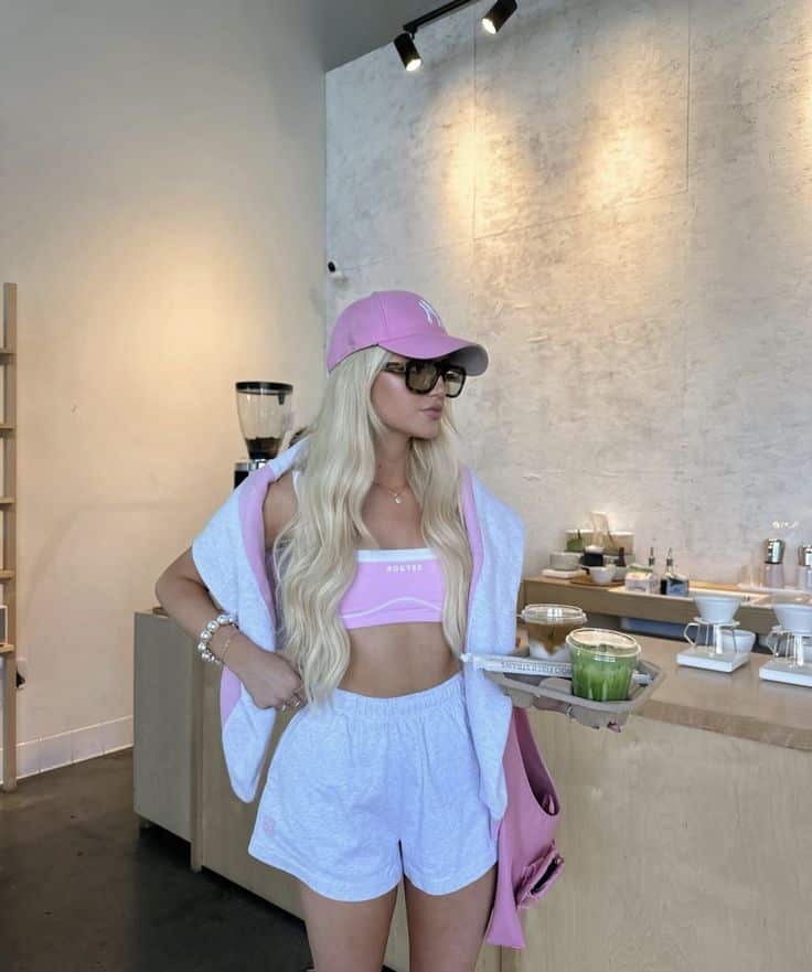 Woman in pink and white outfit with tray of drinks at a modern café.