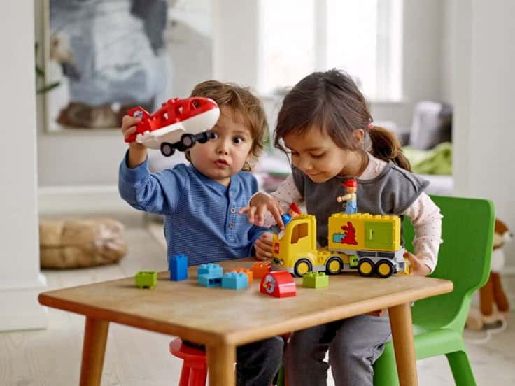 Children playing with colorful Lego toys at a table, building creativity and imagination indoors.