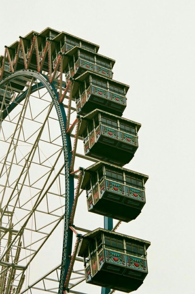 Close-up of a vintage Ferris wheel with ornately decorated gondolas against a clear sky background.