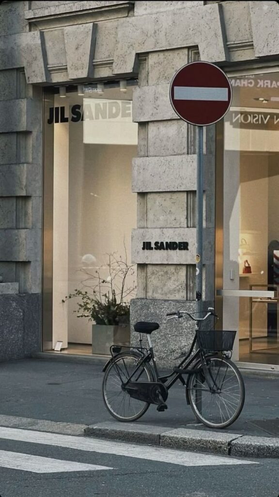 Bicycle parked outside Jil Sander store with do not enter sign nearby.