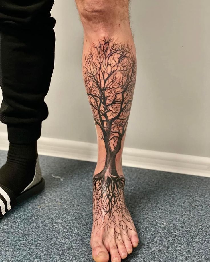 Tree tattoo on calf with intricate branches and roots, blending into foot. Unique leg tattoo design.
