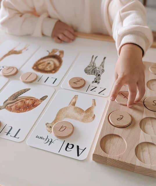 Child playing with animal-themed alphabet puzzle and wooden letters for educational fun.