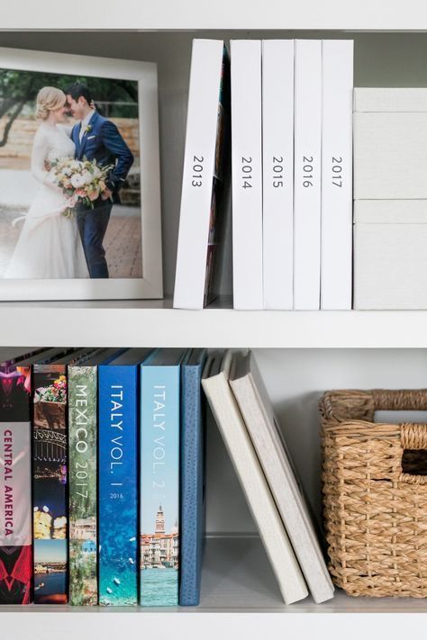 Shelf with travel photo albums, wedding picture, and wicker basket for organized and aesthetic home decor.
