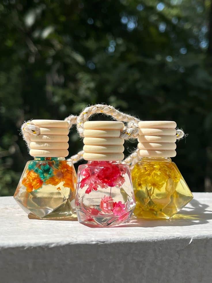Decorative glass bottles with colorful dried flowers and wooden caps displayed outdoors.