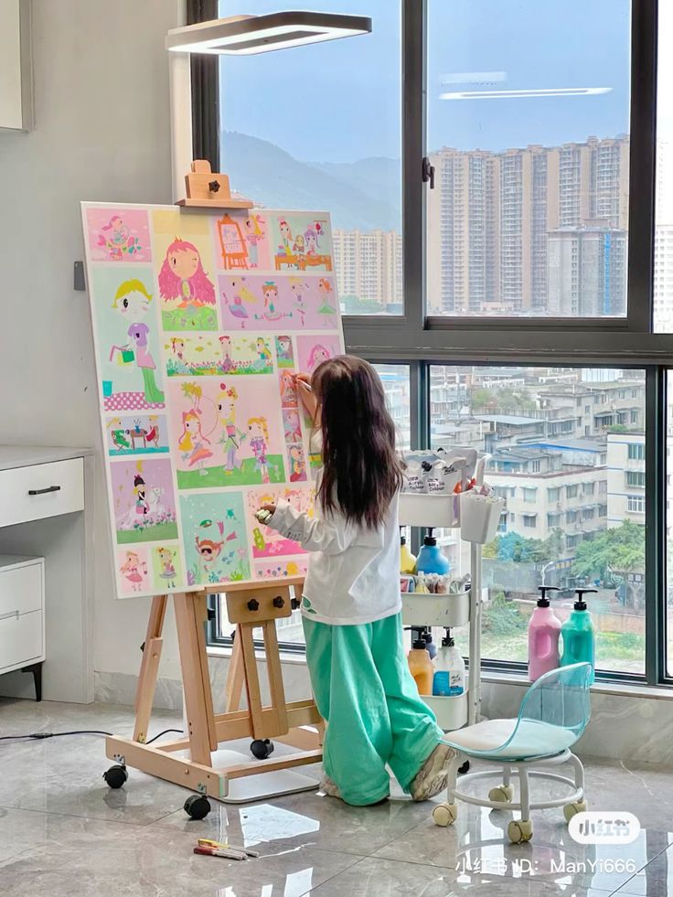 Child painting colorful illustrations on easel in bright, modern art studio with large windows.