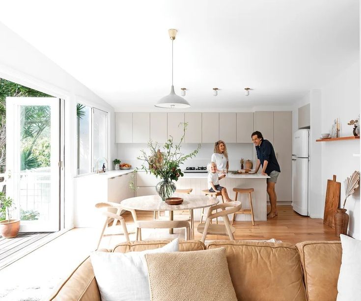 Bright, modern kitchen with family, open doors to patio, wooden flooring, and a cozy dining area.