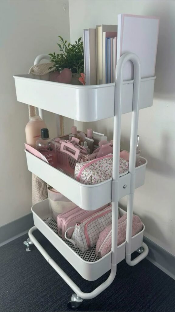 White rolling cart with shelves holding books, plants, toiletries, and accessories in a cozy corner setting.
