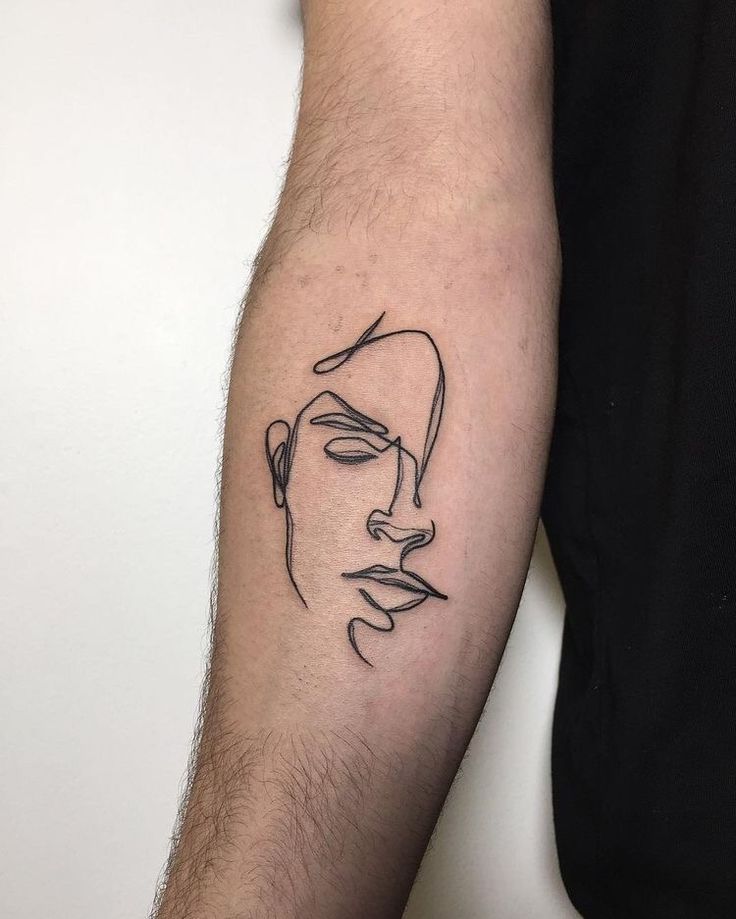 Single line face tattoo on inner forearm, minimalist design with abstract features.