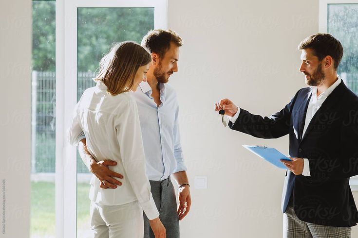 Real estate agent handing keys to a couple in a new home.