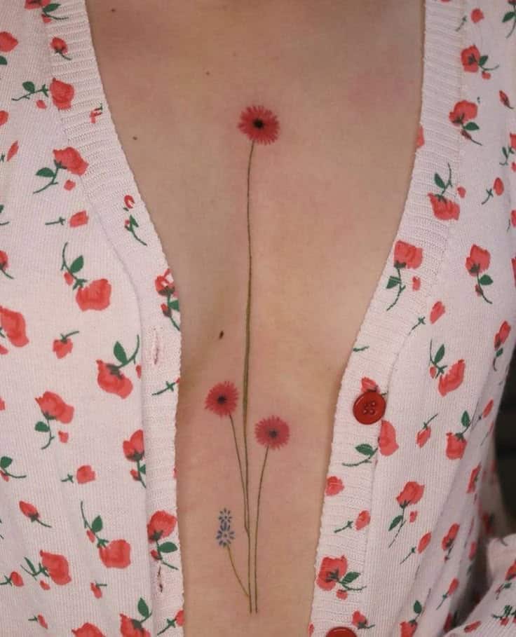 Delicate floral tattoo on chest, featuring red and lavender flowers, with matching floral top background.