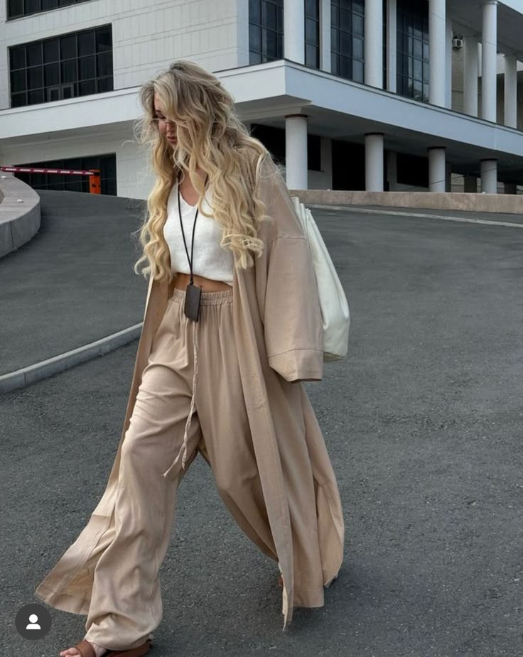 Woman in stylish beige outfit walking outside modern building.