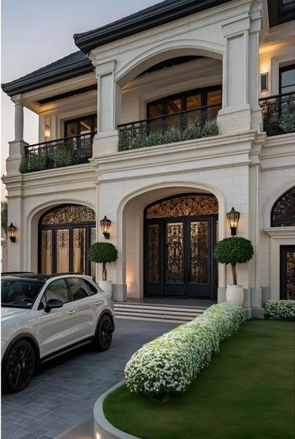 Luxury mansion exterior with modern car in driveway, elegant greenery, and stylish arches.