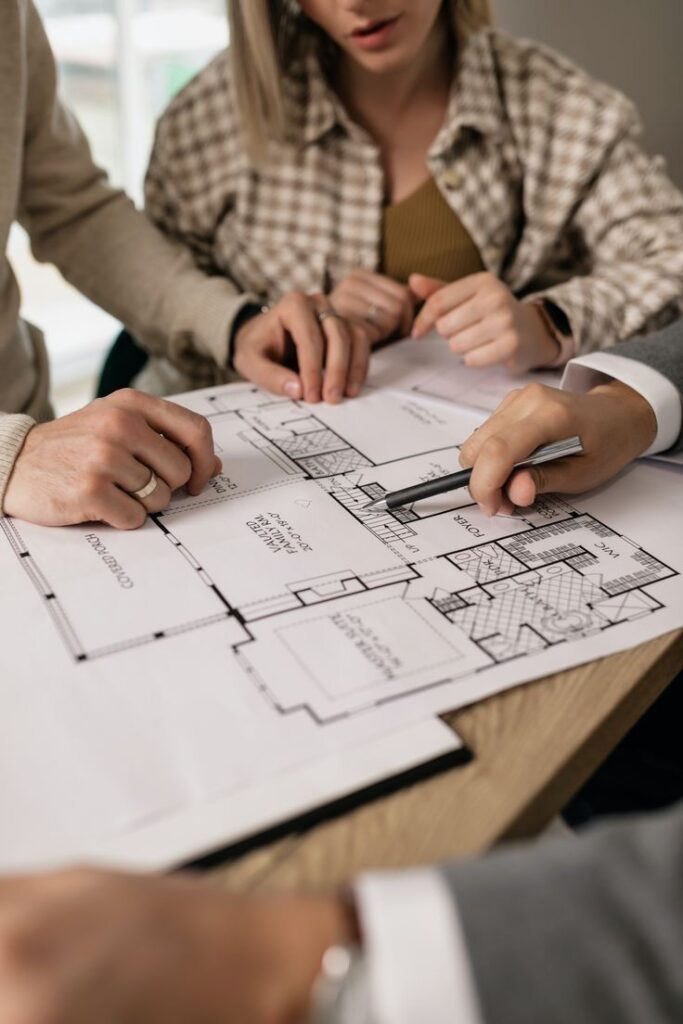 _ 36 Architects reviewing a floor plan together, discussing design details with a pen on desk. | Sky Rye Design Architects reviewing a floor plan together, discussing design details with a pen on desk.