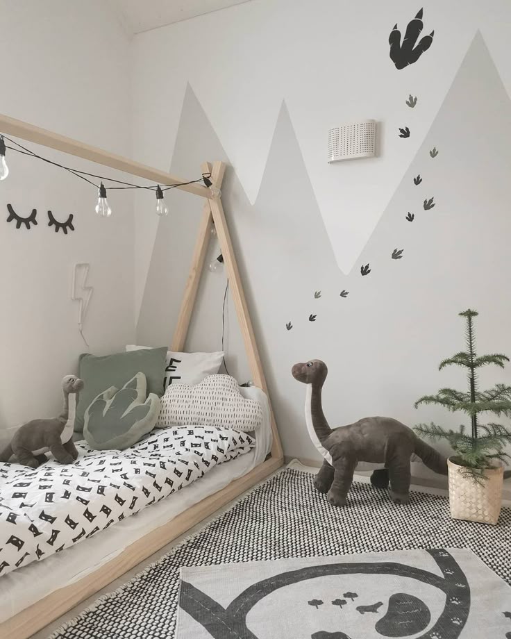 Modern kids' room with dinosaur theme, featuring cozy bed, dinosaur toys, and mountain wall decorations.