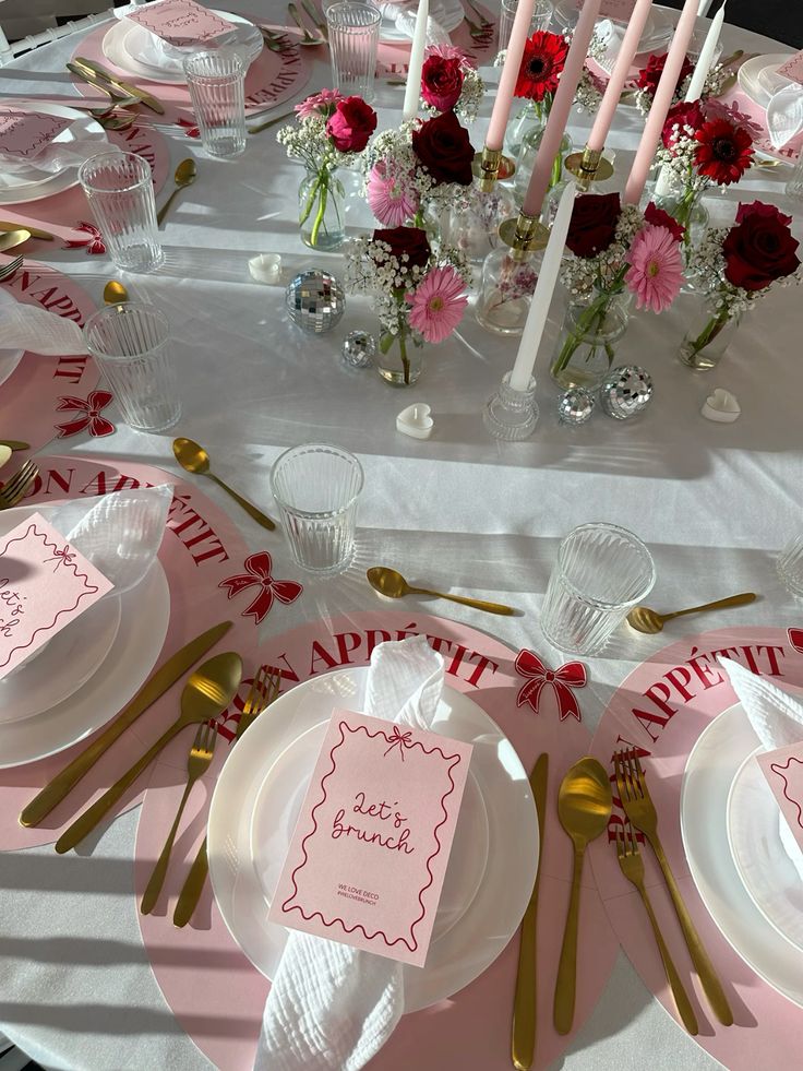 Elegant brunch table setting with pink decor, flowers, golden cutlery, and Let's Brunch cards for a stylish gathering.