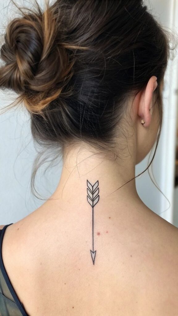 Minimalistic arrow tattoo on back of neck, elegant design with an upward bun hairstyle.