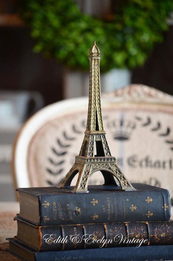 Mini Eiffel Tower on vintage books with blurred background. Paris-themed decor accent for a retro-styled home.
