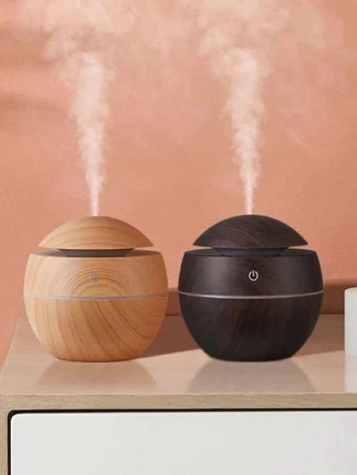 Two wood-grain aroma diffusers releasing steam on a table, creating a calming and stylish home atmosphere.