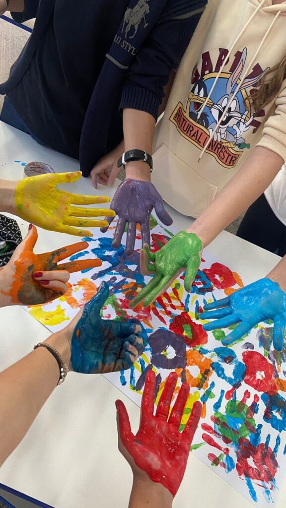 Colorful handprints on paper with painted hands creatively forming vibrant patterns in a fun, artistic activity.